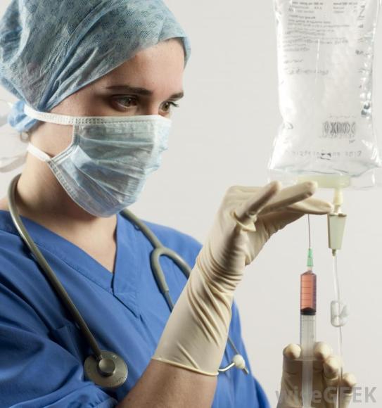 woman in blue scrubs near iv bag with needle